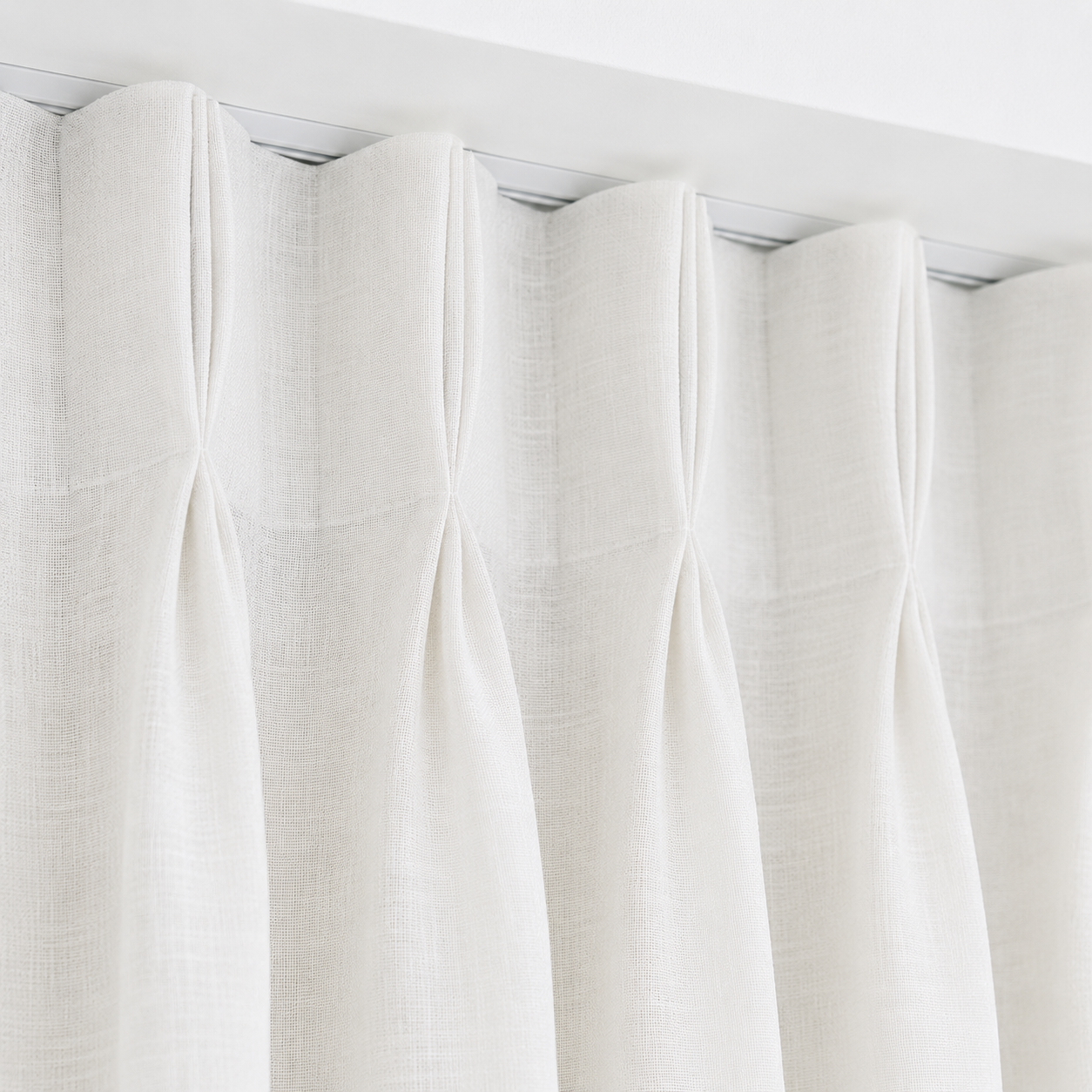 Close-up of white linen pinch pleat curtains with soft textured fabric and ceiling-mounted tracking in a Brisbane home by Security Screens Qld.
