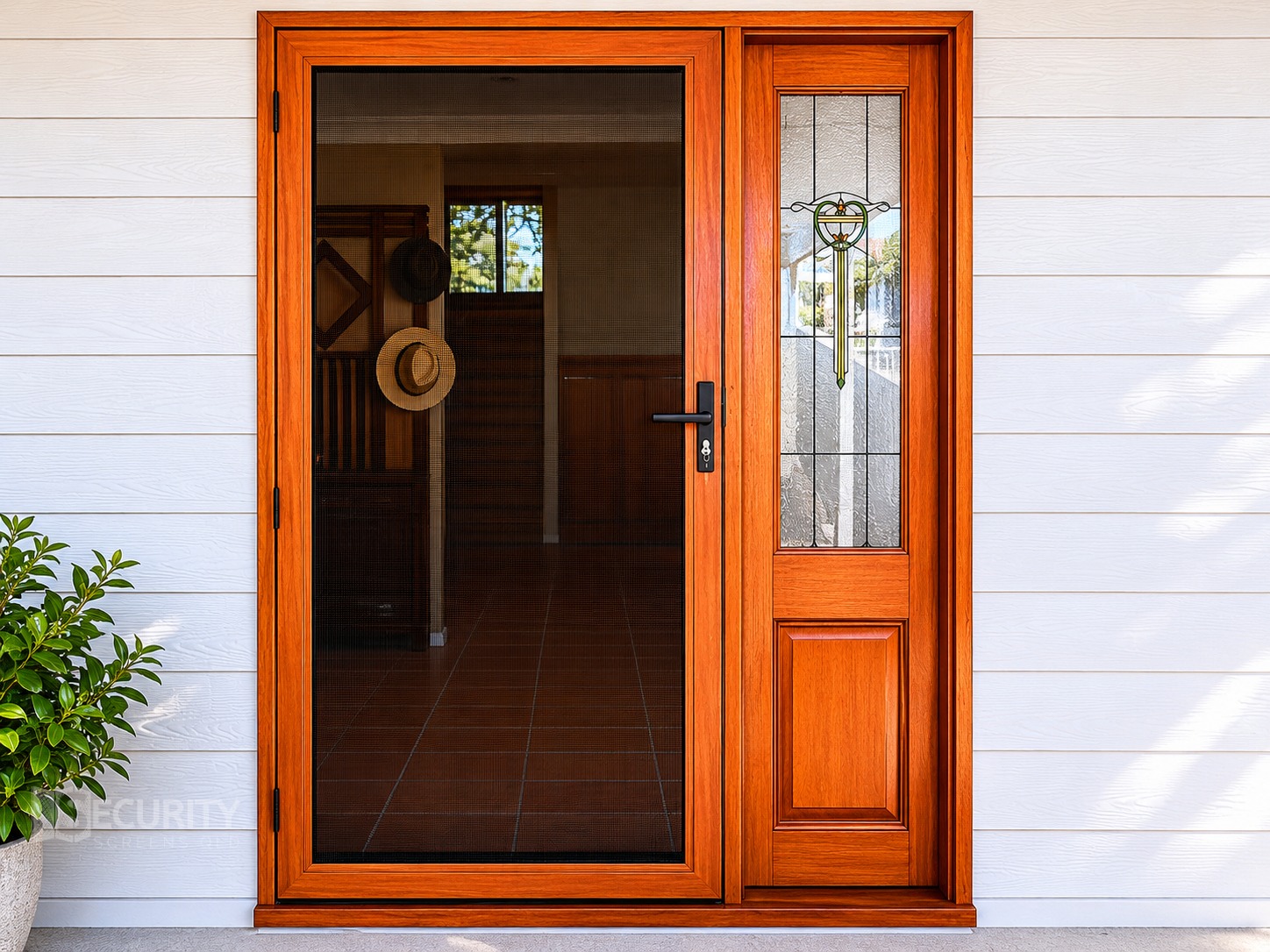 Elegant woodgrain security screen door with hinge installation at residential front entry in Brisbane. Features decorative glass sidelight panel and stainless steel mesh screening.